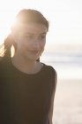 Lächelnde junge Frau schaut am Strand weg — Stockfoto