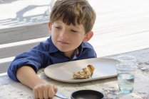 Joyeux petit garçon qui mange à table — Photo de stock