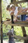 Діти годують собаку дерев'яним будинком — стокове фото