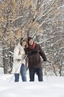Jovem casal snowshoeing na floresta de inverno — Fotografia de Stock