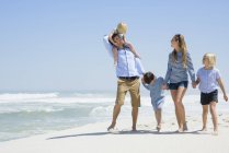 Família relaxada andando na praia arenosa — Fotografia de Stock