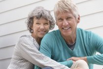 Портрет счастливой пожилой пары, сидящей вне дома — стоковое фото