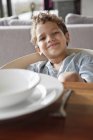 Portrait of smiling little boy sitting at a dining table — Stock Photo