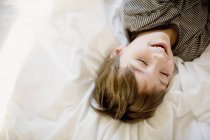 Happy little boy lying on bed with eyes closed — Stock Photo