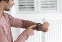 Primer plano del joven que revisa smartwatch - foto de stock