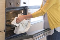 Close-up of Woman removing food tray from oven — Stock Photo