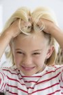 Portrait of little girl scratching hair and looking at camera — Stock Photo