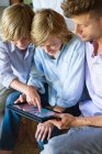 Mann und zwei kleine Jungen schauen auf digitales Tablet — Stockfoto