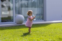 Baby girl drinking water from bottle on lawn — Stock Photo