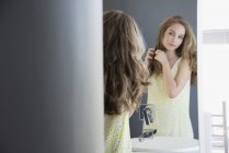 Adolescente examinando el cabello en el espejo - foto de stock