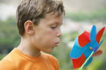 Close-up of boy blowing on colorful pinwheel outdoors — Stock Photo