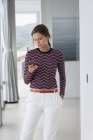 Elegante junge Frau nutzt Smartphone zu Hause — Stockfoto