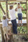 Діти скелелазіння драбини до дерев'яного будинку в саду — стокове фото