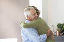 Счастливый старший мужчина обнимает внука-подростка дома — стоковое фото