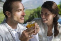 Man smelling marmalade with woman looking in nature — Stock Photo