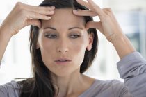 Primo piano della donna che soffre di mal di testa su sfondo sfocato — Foto stock