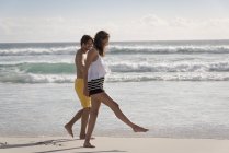 Brincalhão jovem casal andando na praia juntos — Fotografia de Stock