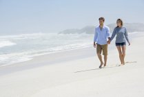 Felice coppia che cammina sulla spiaggia sabbiosa tenendosi per mano — Foto stock