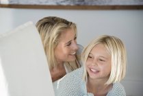 Mãe e filha felizes sorrindo na sala de estar — Fotografia de Stock