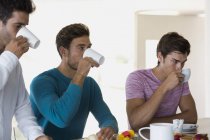 Крупним планом три друзі п'ють каву на кухні — стокове фото