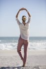 Entspannte junge Frau macht Yoga am sonnigen Strand — Stockfoto