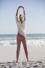 Mujer joven y relajada haciendo yoga en la playa soleada - foto de stock