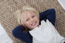 Щасливий маленький хлопчик лежить на плетеному килимку — стокове фото