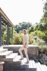 Mulher elegante andando no andar de cima no terraço de madeira no jardim — Fotografia de Stock