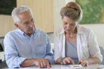 Konzentriertes Senioren-Paar sortiert Rechnungen zu Hause am Tisch — Stockfoto