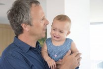 Femmina bambino piangendo tra le braccia del padre a casa — Foto stock