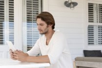 Jeune homme utilisant une tablette numérique sur la terrasse — Photo de stock