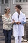 Женщина-медсестра помогает улыбающейся пожилой женщине в доме престарелых — стоковое фото