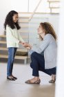 Happy mother and daughter holding hands in front of staircase — Stock Photo