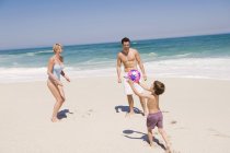 Счастливая семья играет в пляжный мяч на песке — стоковое фото