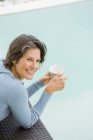Улыбающаяся женщина с чашкой чая у бассейна — стоковое фото