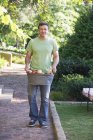 Uomo maturo che trasporta frutta fresca raccolta in cesto in giardino — Foto stock