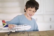 Маленький мальчик играет с моделью самолета дома — стоковое фото
