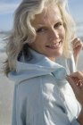 Portrait of smiling mature woman on beach — Stock Photo
