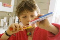 Крупним планом хлопчик тримає зубну пасту і зубну щітку — стокове фото