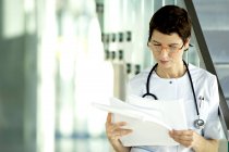 Жінка-лікар читає медичні записи в клініці — стокове фото