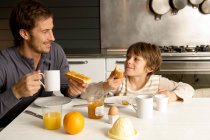 Середній дорослий чоловік снідає зі своїм сином — стокове фото