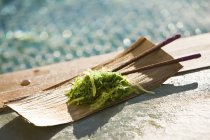 Close-up de algas com pauzinhos em bandeja de madeira à beira da piscina — Fotografia de Stock