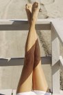 Женские ноги лежат на деревянных перилах балкона на открытом воздухе и загорают — стоковое фото