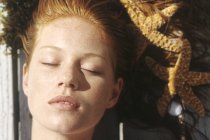 Visage de jeune femme couchée à l'extérieur et bronzant — Photo de stock