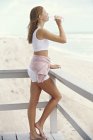 Молодий slim рудоволосої жінку, що стоїть на балконі з пляшкою води в приморських — стокове фото