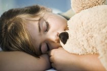 Nahaufnahme eines kleinen Mädchens, das mit Teddybär schläft — Stockfoto