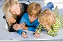 Donna aiutare i suoi figli nei loro compiti — Foto stock