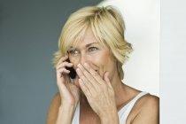 Удивленная взрослая женщина разговаривает по мобильному телефону — стоковое фото