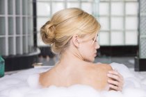 Visão traseira da mulher loira tomando banho de espuma — Fotografia de Stock