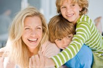 Mujer sonriendo con sus dos hijos - foto de stock